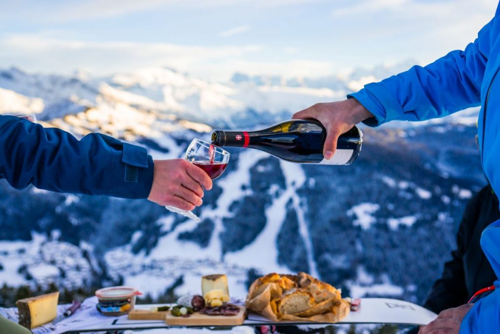Savoie Cheese Route - pouring a glass of red wine to enjoy with cheese by the ski slopes of Les Gets