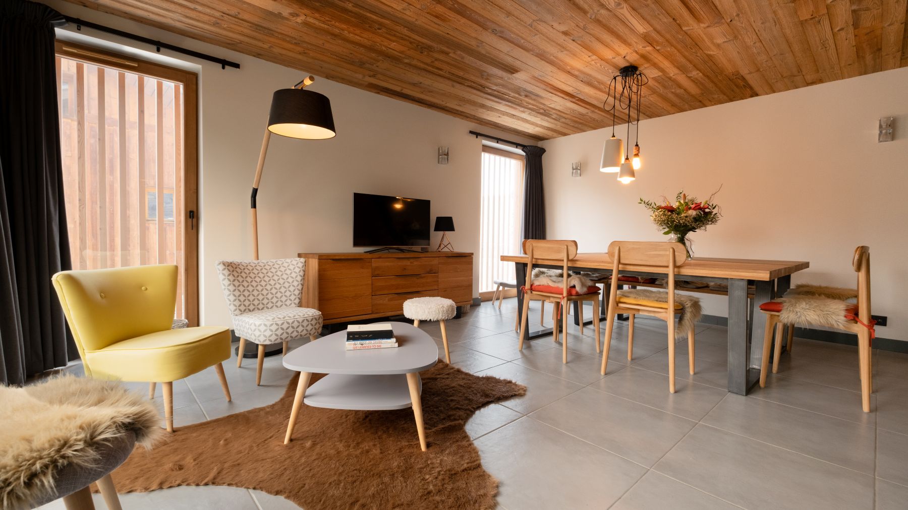 Chalet Caro, Meribel - kitchen with dining table and armchairs round a coffee table