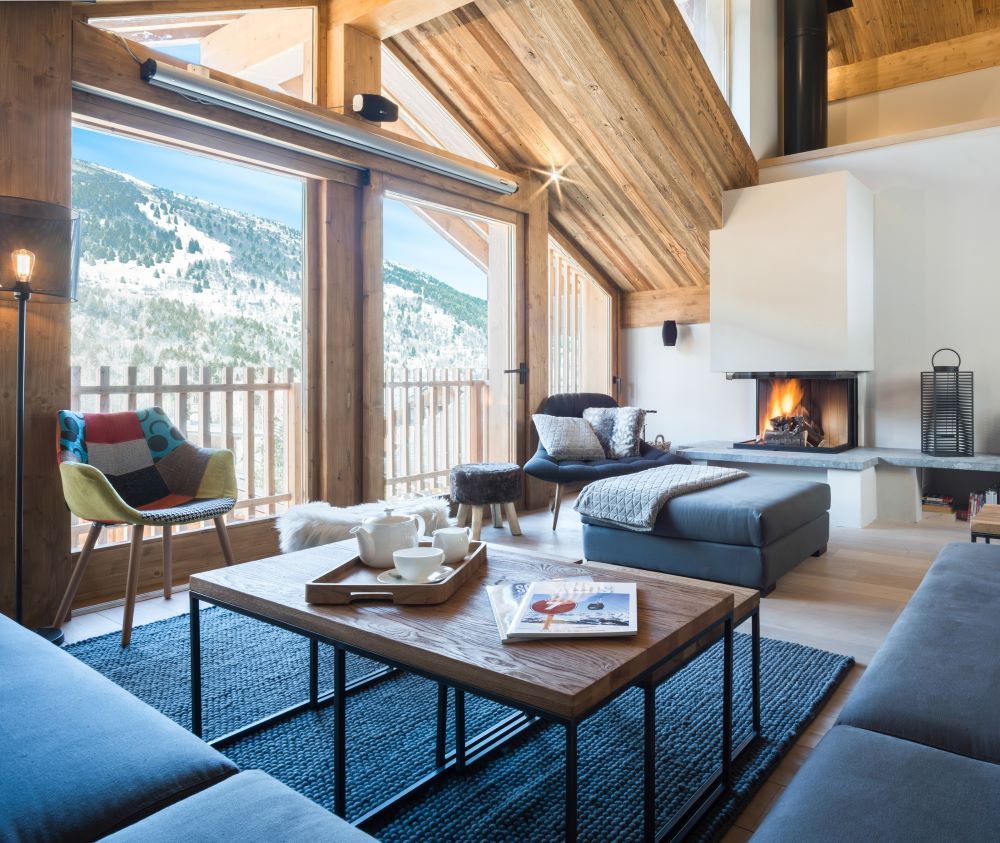 Chalet Caro, Meribel - lounge with large sofas, fireplace and large windows