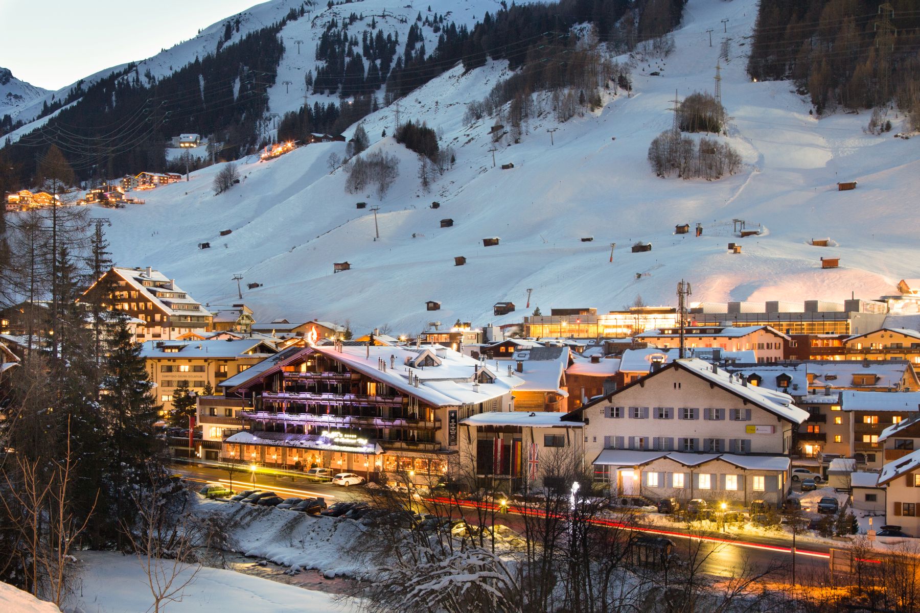 Raffl's St Antoner Hof, St Anton - hotel exterior at dusk with ski slopes in the background